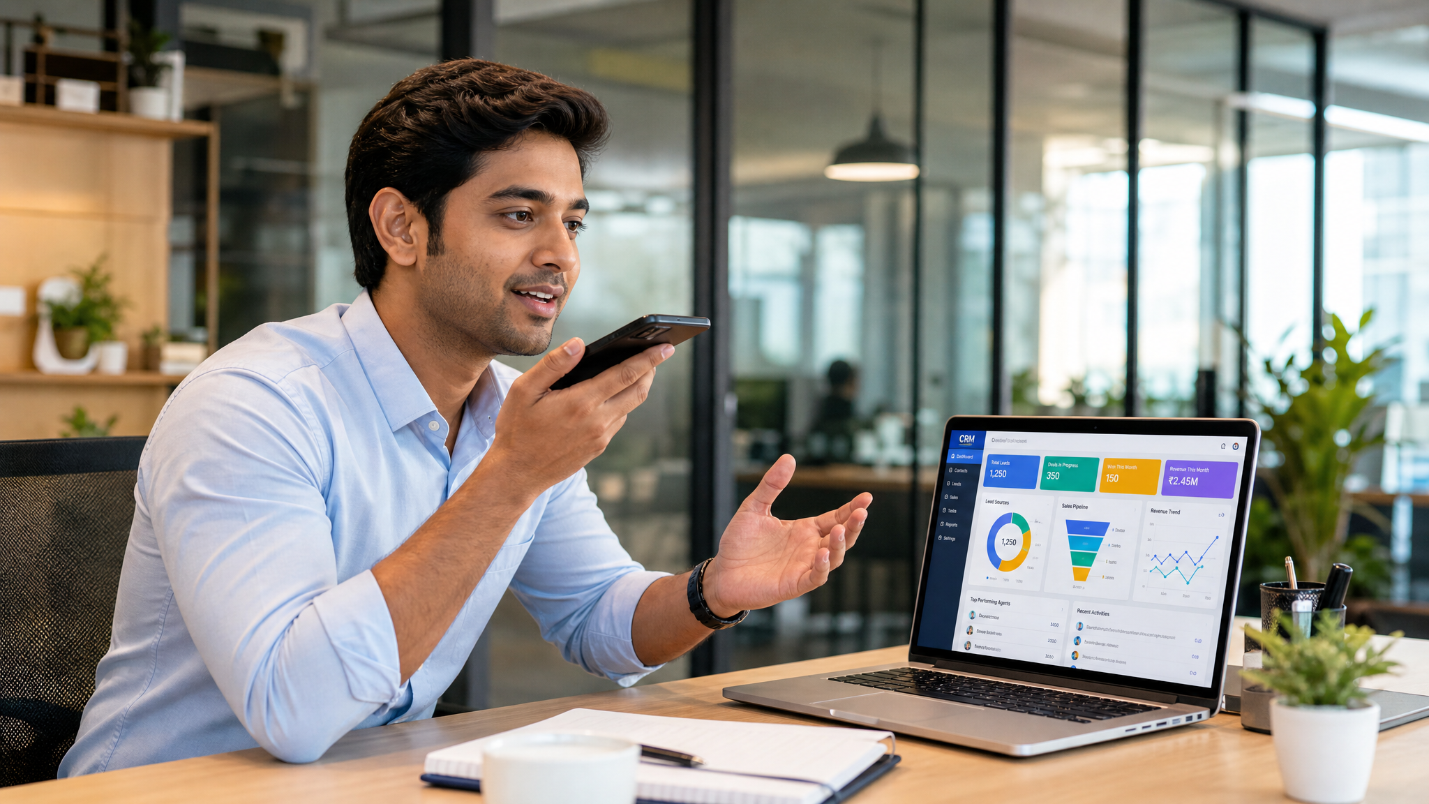 Indian salesperson using voice-powered CRM on his phone while working at his desk